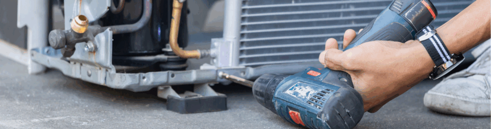 A close up image of an Always Plumbing & Heating technician taking the exterior panel off an AC unit so he can get a better look at the interior components.